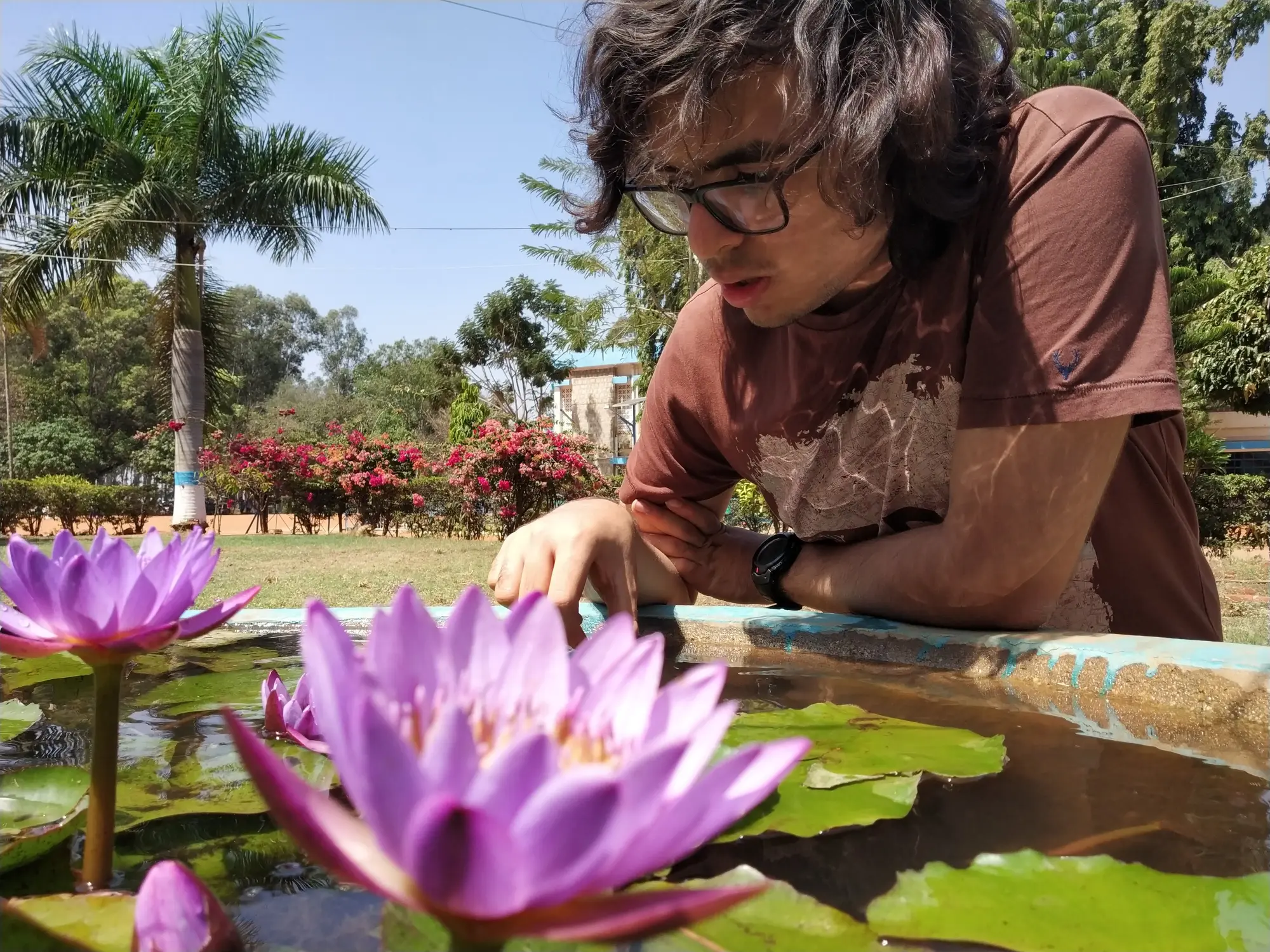 Picture of Pranshu looking at purple lotuses in a pond