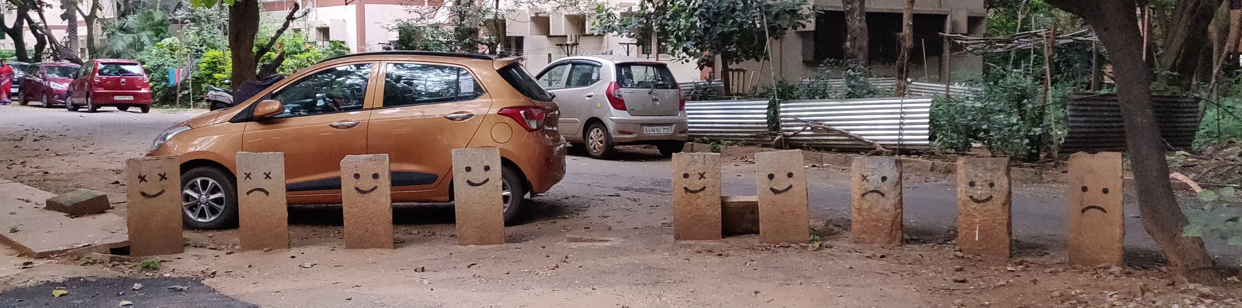 Nine bollards, each with eyes and a mouth spray painted on.