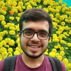 Portrait of Pranshu Gaba standing in front of yellow flowers.