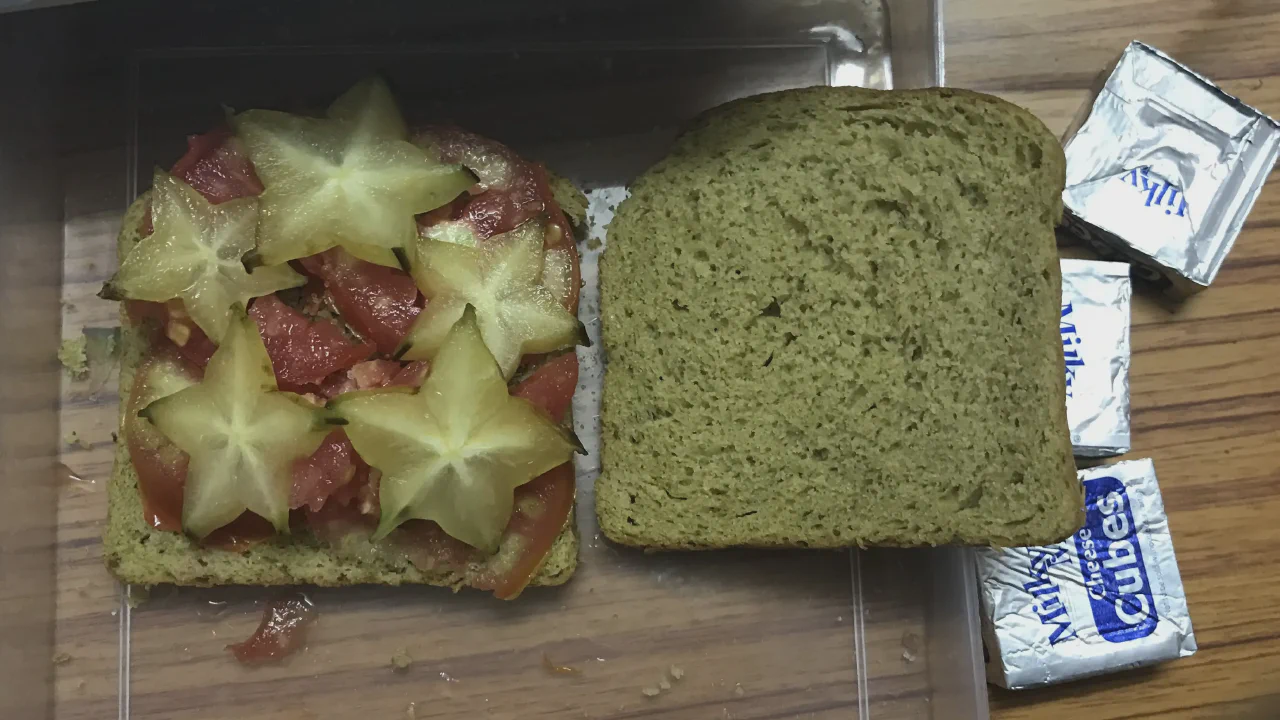 Tomato and starfruit slices placed on a slice of bread.