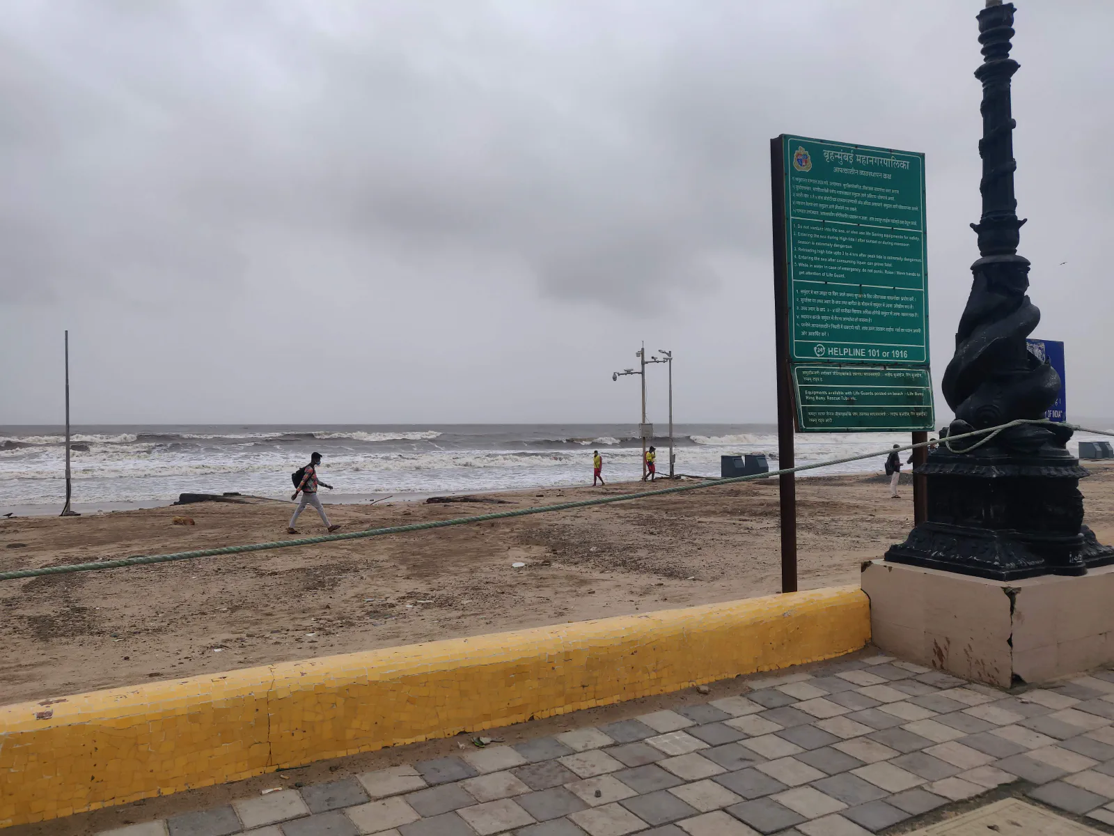 A person walking across a mostly deserted Juhu Beach