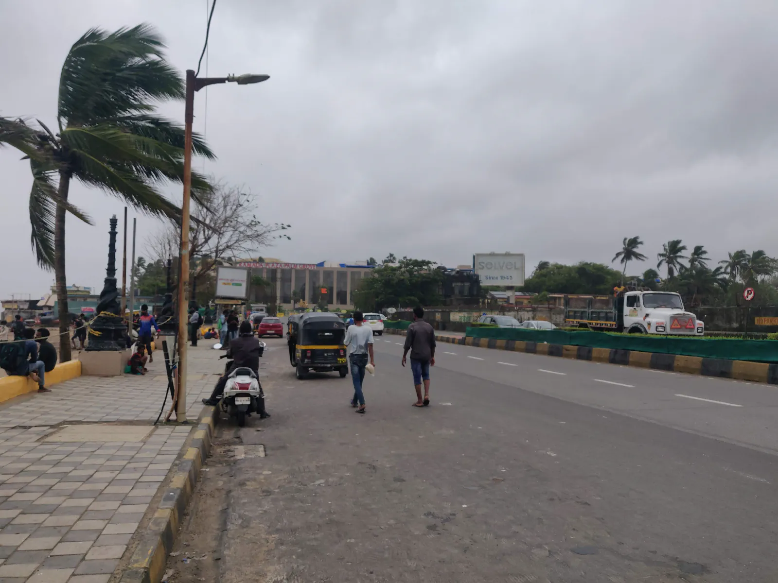 People walking on Juhu Road next to Juhu Beach