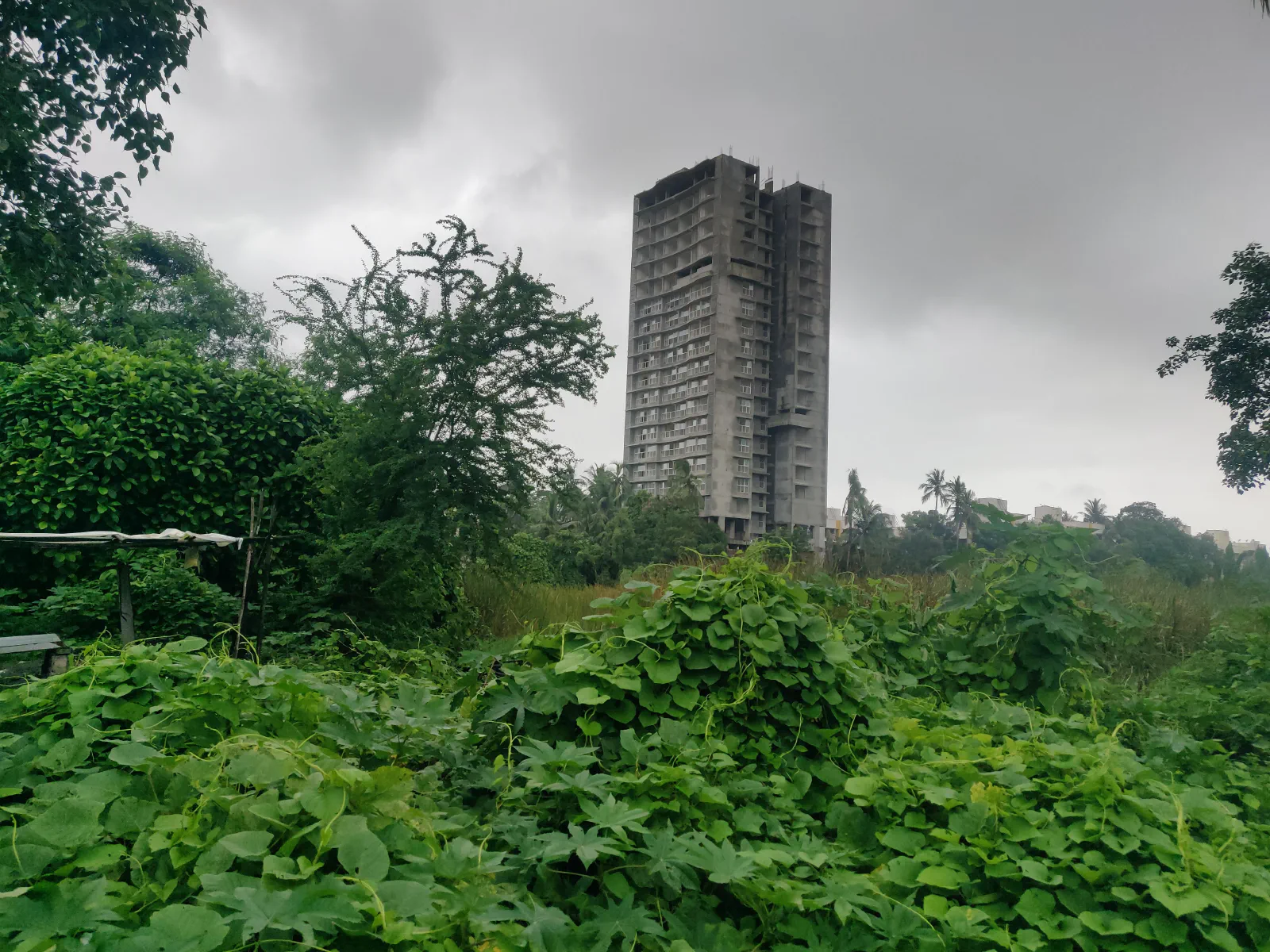Tall grey building in a green field.