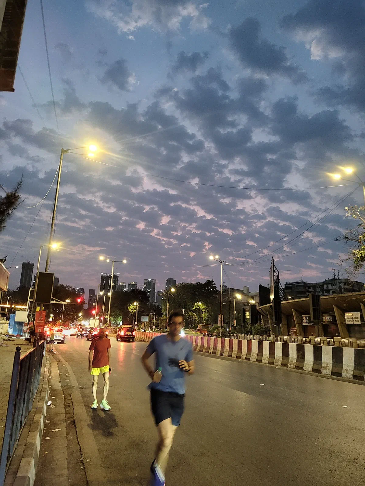 People jog on the road, with clouds in the backdrop.
