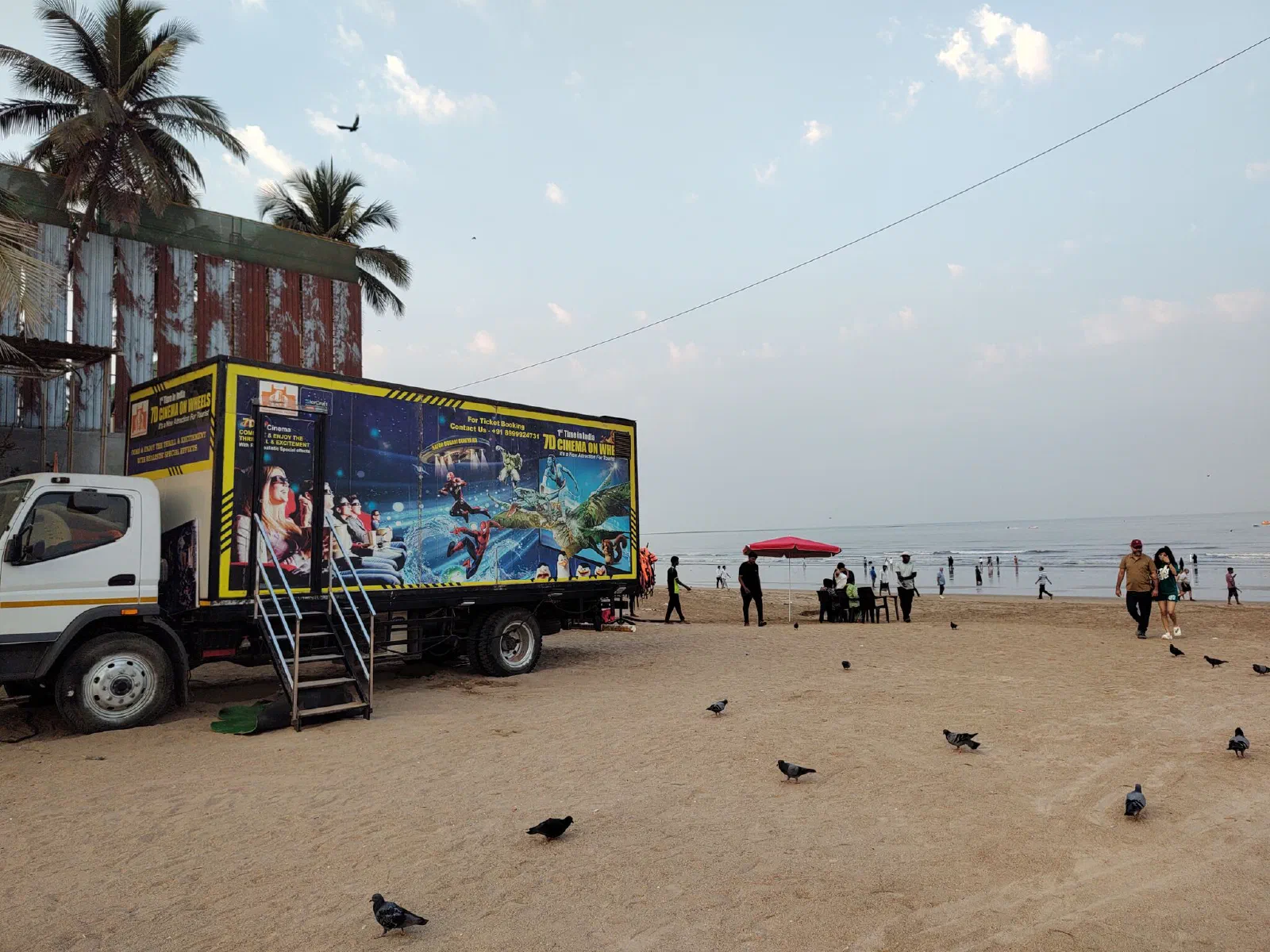 A truck parked on the beach with a sign "7D cinmea on wheels".
