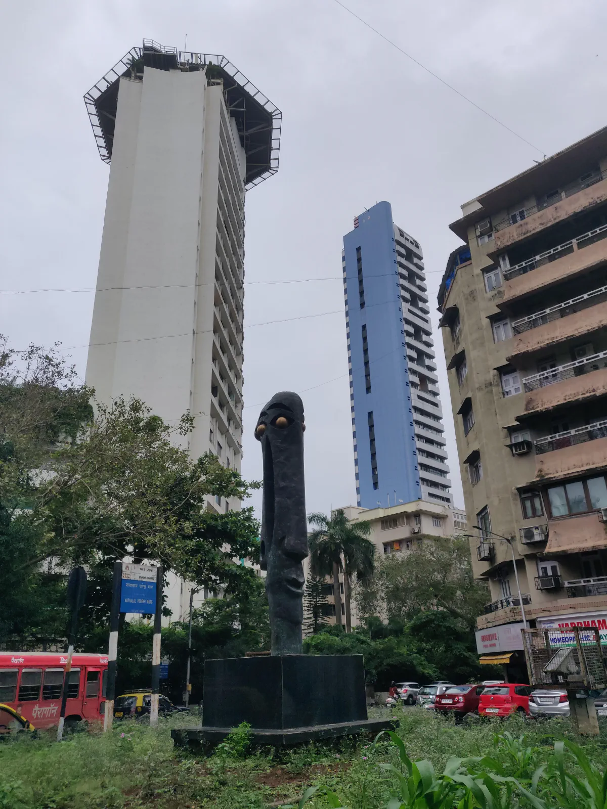 A black statue in front of a white and a blue skyscrapers.